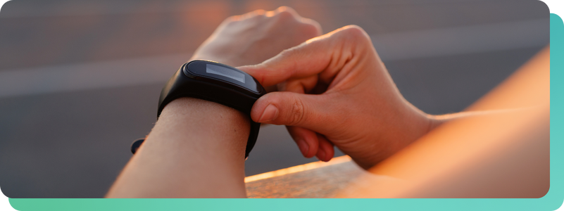 Person checking fitness tracker on wrist during outdoor workout at sunset