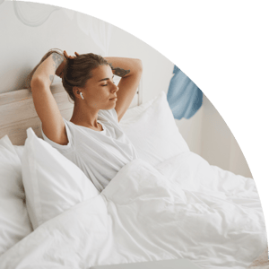 Woman in bed with earbuds listening to sleep music