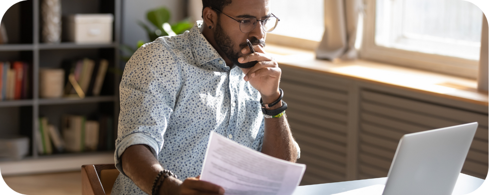 Man with paperwork at computer trying to figure out music licensing reporting and compliance (1)