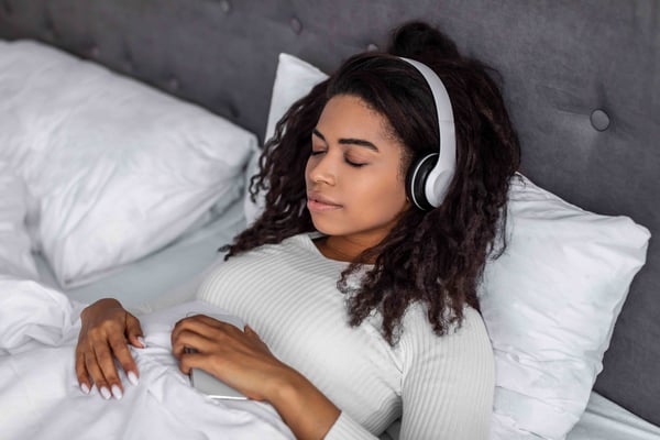 woman in bed listening to music with headphones