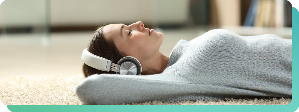 Woman lying on carpet listening to wellness music on headphones-1